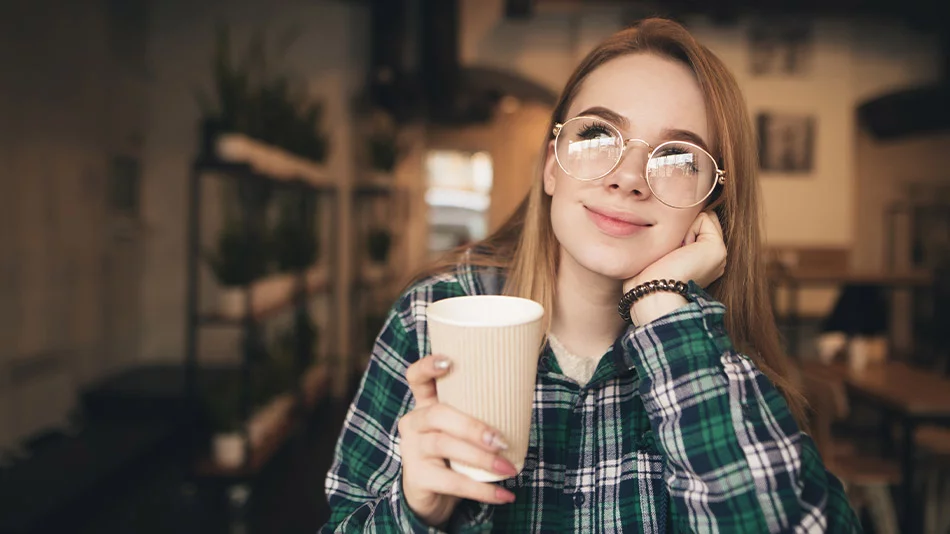 A young, beautiful woman with glasses thinking about getting ICL surgery.